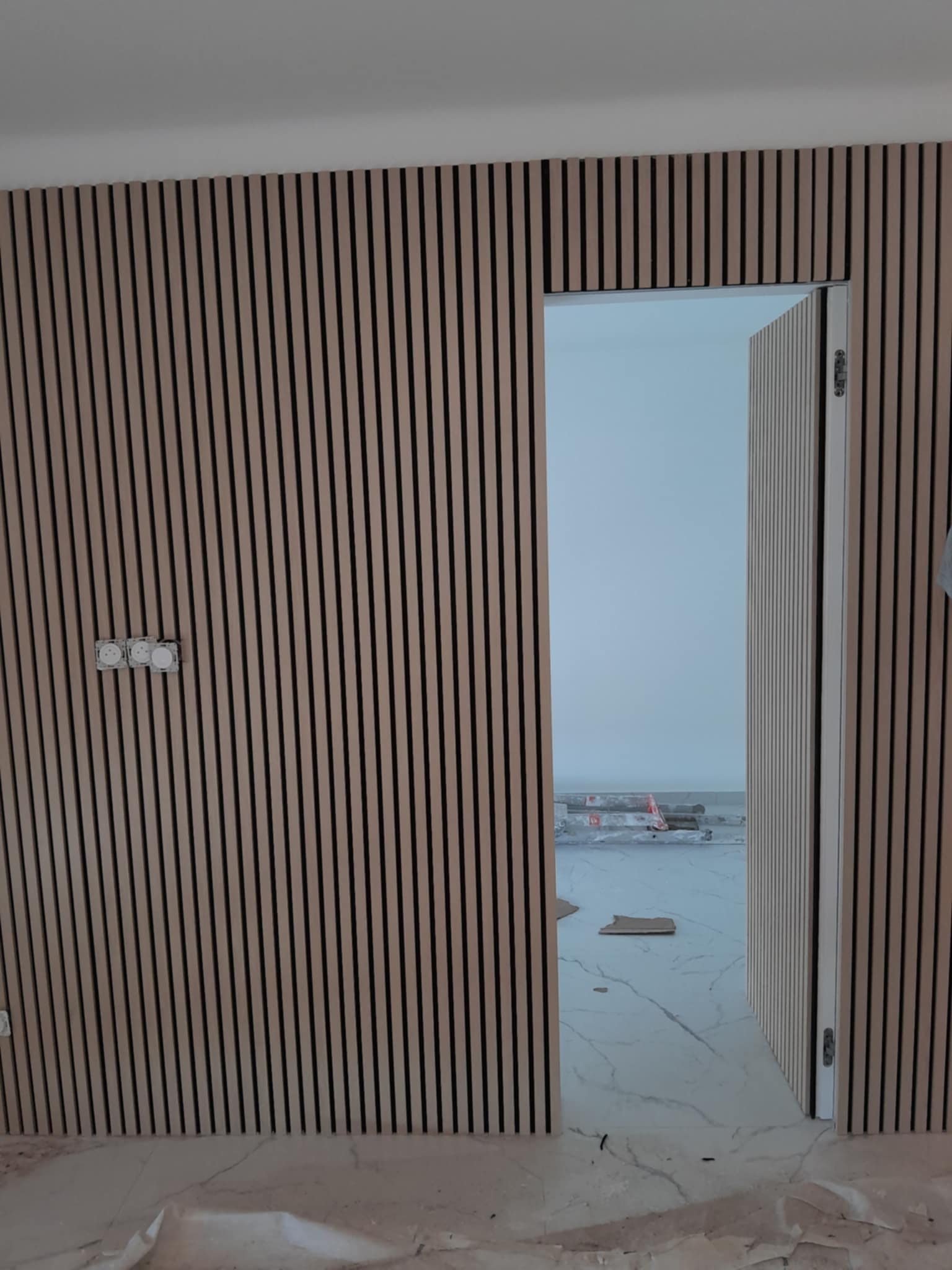 Habillage d’une cloison et d’une porte avec des tasseaux de bois décoratifs